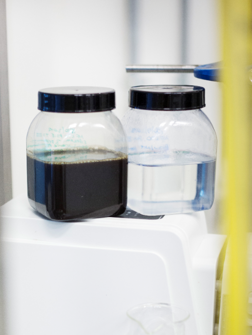 two plastic containers, one with a clear liquid one with a black liquid